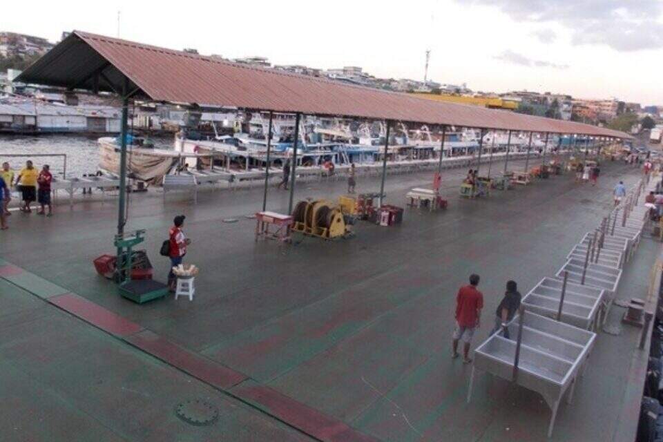 Terminal pesqueiro de Manaus com cobertura central e plataforma cercada de barcos de pesca